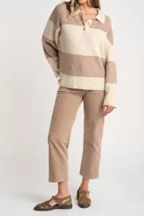 Sweater de punto con cuello polo y cierre frontal de tres botones. Presenta un diseño de corte oversize, mangas largas y textura acanalada.