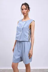 Chaleco celeste con diseño cruzado y doble botonadura, sin mangas y con apliques de encaje en los laterales.