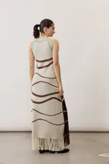 Vestido largo de punto con diseño geométrico y de ondas en color negro y crudo, sin mangas, con escote halter y detalle de flecos en el ruedo.