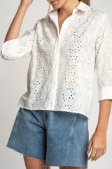 Camisa blanca de algodón con bordado calado tipo broderie, corte recto, cuello camisero y mangas 3/4.