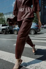 Pantalón tobillero de tiro medio color marrón oscuro, con cintura elástica ajustable con cordón y herretes dorados. Incluye bolsillos delanteros y bolsillos de plastrón en la espalda.