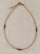 Collar tipo gargantilla elaborado con cuentas de cristal en tono rosa pálido, intercaladas con cuentas en tonos oscuros y detalles metálicos dorados. Cuenta con cadena extensora.
