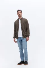 Campera de tejido de punto liviano color beige, con cierre frontal completo y cuello alto tipo bomber. Presenta un pequeño logo bordado en el pecho y puños acanalados.