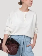 Sweater de punto color beige claro, con escote redondo y cierre frontal parcial de botones con reborde metalizado, mangas largas abullonadas y puños y ruedo elásticos.