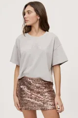 Remera gris de fit amplio, con mangas cortas y cuello redondo. Presenta efecto lavado y estampa frontal con aplicación de strass con la frase "fiesta mode on".