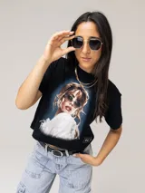 Remera crop negra de manga corta, con cuello redondo y estampado fotográfico frontal de Tini con efecto vintage y detalles de la colaboración con Under Armour.