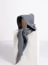 Bufanda de punto gris con capucha integrada, diseñada con un tejido de textura suave y terminaciones en punta.