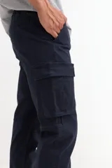 Pantalón tipo jogger cargo de hombre, color verde militar, con cordón ajustable en la cintura y puños elásticos en los tobillos. Presenta bolsillos cargo con solapa en ambos muslos.