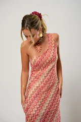 Vestido midi de crochet con diseño de ondas en tonos rojo, rosa y beige. Tiene un solo hombro y tajos laterales.