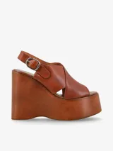 Sandalia de cuero color marrón con plataforma de madera y tira trasera ajustable con hebilla.