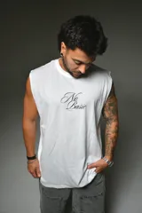 Musculosa blanca de corte holgado, con cuello redondo y diseño sin mangas. Presenta un estampado tipográfico en el pecho con la frase 'No Basic' en color negro.