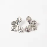 Par de caravanas de diseño floral con acabado metálico plateado brillante y superficie texturizada.