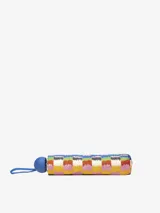 Paraguas plegable con estampado multicolor de rayas verticales con efecto pincelada, que simula un patrón de cuadros en tonos vibrantes como azul, amarillo, rosa, naranja y blanco. Posee un mango y correa de sujeción de color azul sólido.