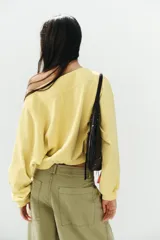 Sudadera de algodón con efecto lavado en color amarillo, cuello barco, abertura frontal con botones a presión y manga larga.
