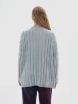 Buzo tejido de punto color beige, con cuello subido, diseño oversized y aberturas laterales en el ruedo.