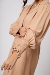 Vestido corto color tostado, con cuello solapa, abotonado al frente y mangas 3/4 con puños fruncidos.