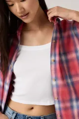 Camisa de franela a cuadros en tonos rojo, azul y blanco, con cuello clásico, cierre de botones frontales y un bolsillo en el pecho.