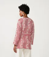 Cárdigan largo de punto con estampado geométrico en tonos rojo y blanco, manga larga, lazo en la cintura y abertura frontal sin botones.