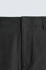 Pantalón de corte balloon fit, color negro, con bolsillos laterales de vivo y bolsillos traseros con solapa. Presenta cierre frontal con cremallera y botón.