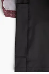 Short deportivo de doble capa, con calza interior. El short exterior es de color borgoña con un estampado sutil de puntos en forma de camuflaje. Posee cintura elástica con cordón oculto y aberturas laterales. La calza interior es negra.