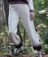 Pantalón jogger de punto color blanco marfil, confeccionado en lana merino, con tiro alto, cintura elástica y diseño con bloque de color marrón y detalles geométricos en el bajo.