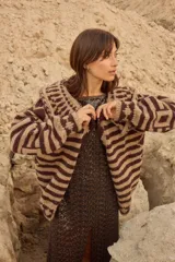 Saco de punto con diseño geométrico y rayas horizontales, cuello amplio y botones artesanales. Presenta una combinación de colores chocolate y beige.