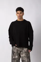 Sweater negro de calce relajado con diseño de textura combinada, presentando un lado liso y otro con tejido de ochos. Posee cuello redondo y mangas largas.