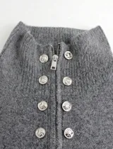 Cardigan de punto gris con cuello alto, cierre frontal de cremallera y doble hilera de botones decorativos metálicos. Diseño de manga larga y corte recto.