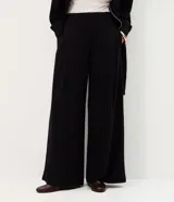 Pantalón wide leg negro con diseño a rayas sutiles, tiro medio, pinzas frontales y caída fluida.