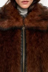 Chaqueta corta de corte globo confeccionada en pelo sintético color marrón, con cierre frontal de cremallera metálica y cuello camisero amplio. Presenta manga larga recta y bolsillos laterales de vivo.