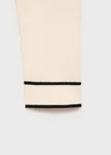 Jersey de punto fino en color crema con cuello de pico y detalles en contraste color marrón en el cuello y los puños. Presenta un diseño recto de manga larga.