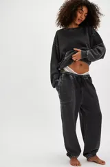 Pantalón de jogging negro con efecto gastado (acid wash), tiro medio y silueta relajada con puños ajustados en los tobillos. Presenta cordón de ajuste en la cintura y costuras visibles en contraste.