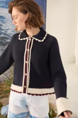 Cardigan de punto azul marino con cuello tejido a mano en crochet color crudo, cierre frontal con botones y detalles en tono borravino y crudo en los bordes y puños semióxford.