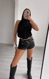 Top negro sin mangas con cuello alto y diseño cruzado en el frente, confeccionado en tela fluida.