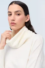 Polera color crema de tejido de punto jersey, con cuello amplio y mangas largas.