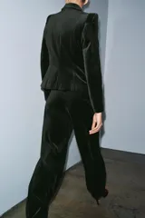 Blazer entallada de Zara Woman Collection confeccionada en tejido de terciopelo. Presenta cuello con solapas de muesca, manga larga con hombreras, bolsillos delanteros con solapa y cierre frontal con un botón. Incluye forro interior.