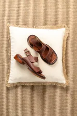 Sandalias de cuero marrón con diseño de punta abierta, tiras ajustables con hebilla metálica y suela de bloque bajo.