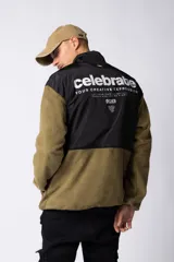 Campera de polar con recortes en tela técnica tipo sire en la parte superior frontal. Presenta cierre frontal completo, cuello alto y bolsillos funcionales en el pecho. Diseño bicolor en tonos verde oliva y negro con logo de la marca en el pecho.