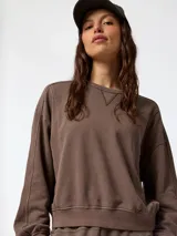 Buzo oversize marrón con cuello redondo, detalles de costuras visibles y puños y cintura de rib elástico.