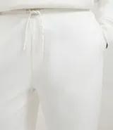 Pantalón jogger negro de algodón y poliéster, con cintura elástica y cordón ajustable. Presenta bolsillos laterales y puños ajustados en los tobillos.