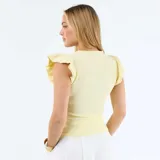 Camiseta acanalada de color amarillo pastel, con cuello redondo y mangas cortas adornadas con volantes.
