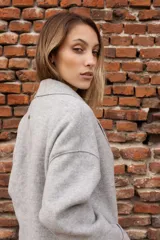 Tapado de paño color rosado, de corte oversized y diseño cruzado. Presenta solapas clásicas, mangas largas con puños vueltos y amplios bolsillos delanteros. Cierre frontal con un botón visible.