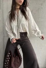 Camisa beige de manga larga, con detalles bordados en el frente y botones decorativos.