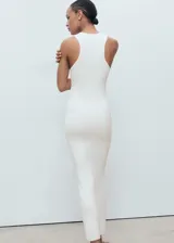 Vestido largo de punto color blanco, de corte entallado, con cuello halter y sin mangas.