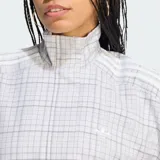 Campera Adidas de corte oversize y mangas voluminosas, con cuello alto, cierre frontal y diseño a cuadros en color gris.