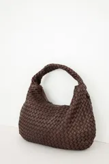 Bolso tipo hobo de cuero marrón oscuro, con diseño trenzado y asa integrada al hombro.