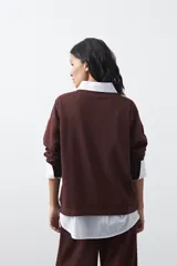 Buzo de manga larga color marrón chocolate, con silueta relajada, hombros caídos y diseño minimalista. Confeccionado en tejido suave con caída fluida.