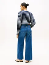 Jean de Tommy Hilfiger confeccionado en denim rígido, con corte de pierna ancha y talle alto. Presenta un diseño clásico de cinco bolsillos, cierre de cremallera con botón y un sutil efecto desteñido en muslos y rodillas.