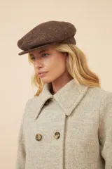 Boina con visera de lana fina uruguaya natural, sin teñir, con diseño de tejido texturizado en tonos beige y marrón.