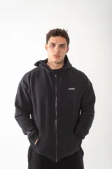 Campera con cierre frontal metálico, confeccionada en algodón pesado de alto gramaje. Presenta un diseño oversize con capucha, bolsillos tipo canguro y bordados minimalistas en el frente y en la manga.